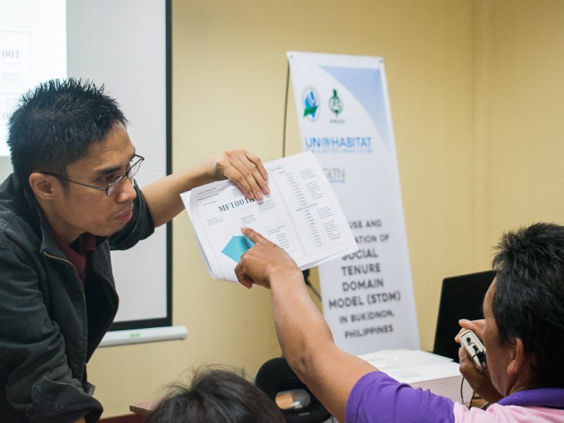 Josh Atienza, the tech consultant for Social Tenure Domain Model (STDM) software, explains the coding to Datu Richard Dawatan of PTTA (lower right).