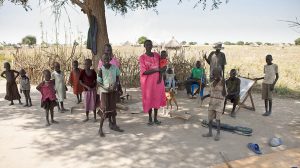 A family stands in the shade of a tree in Liliir, South Sudan @ Shutterstock/John Wollwerth